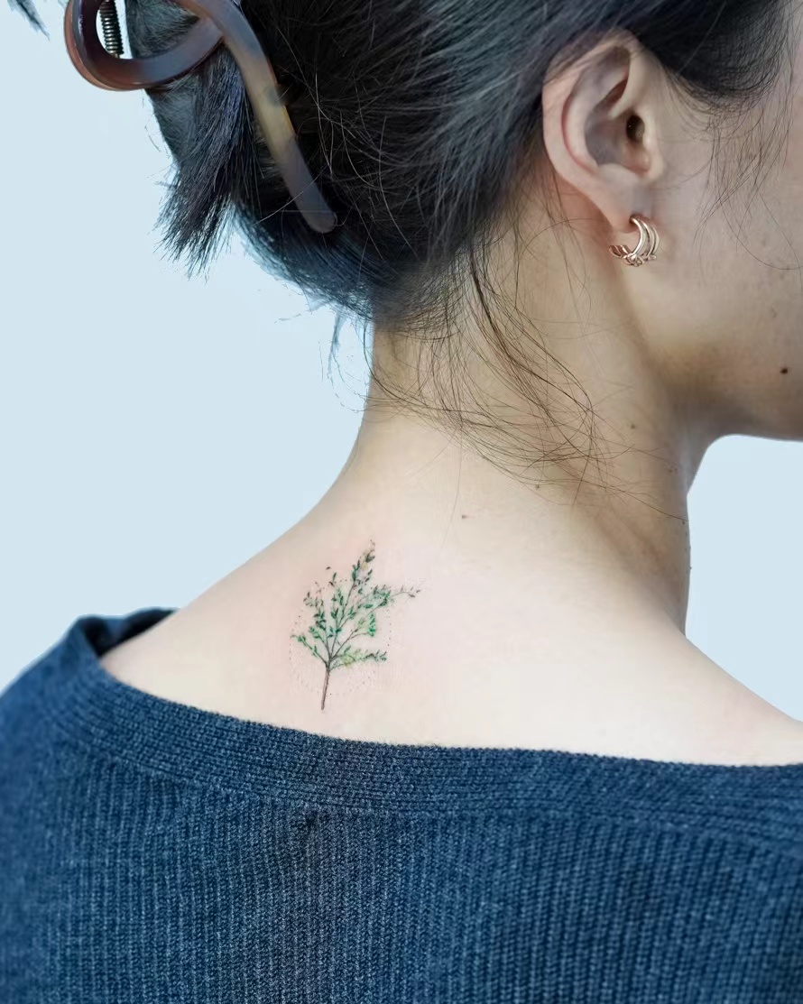 Small green botanical tattoo on upper back