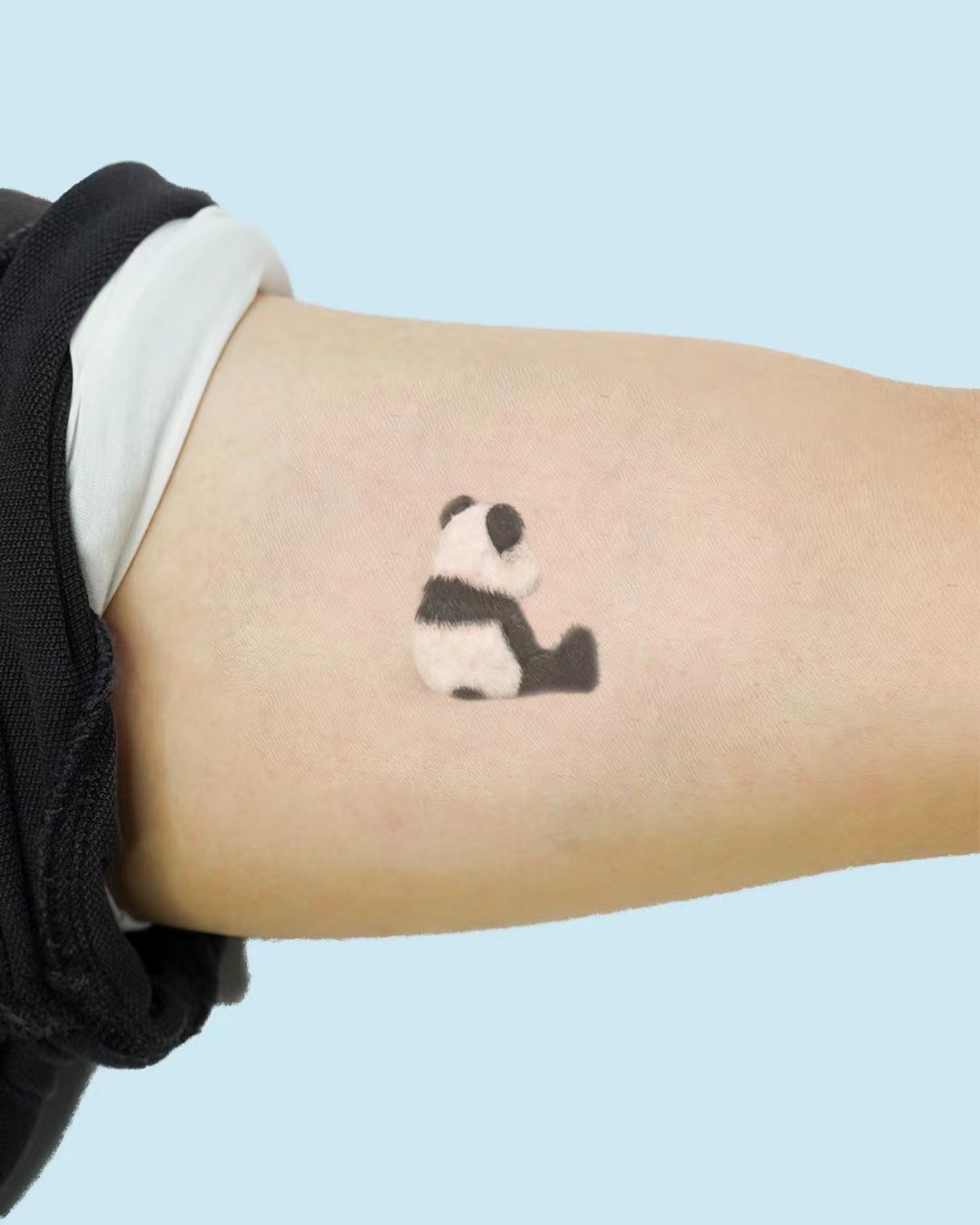 Soft panda tattoo on skin with blue background