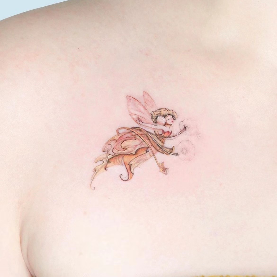 Tiny fairy tattoo with soft pink and golden details