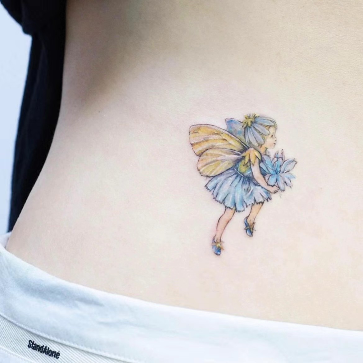 Delicate fairy and flower colour tattoo on torso