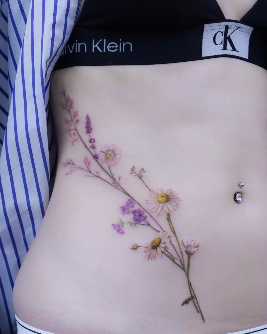 Fine botanical colour tattoo flowing along the ribs