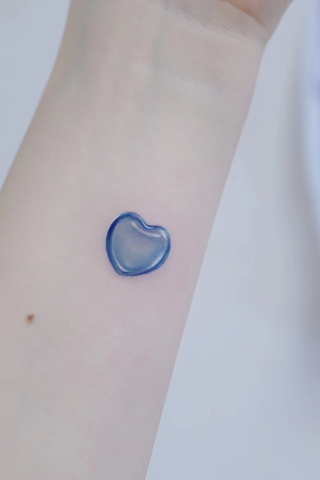 Small blue heart tattoo on arm