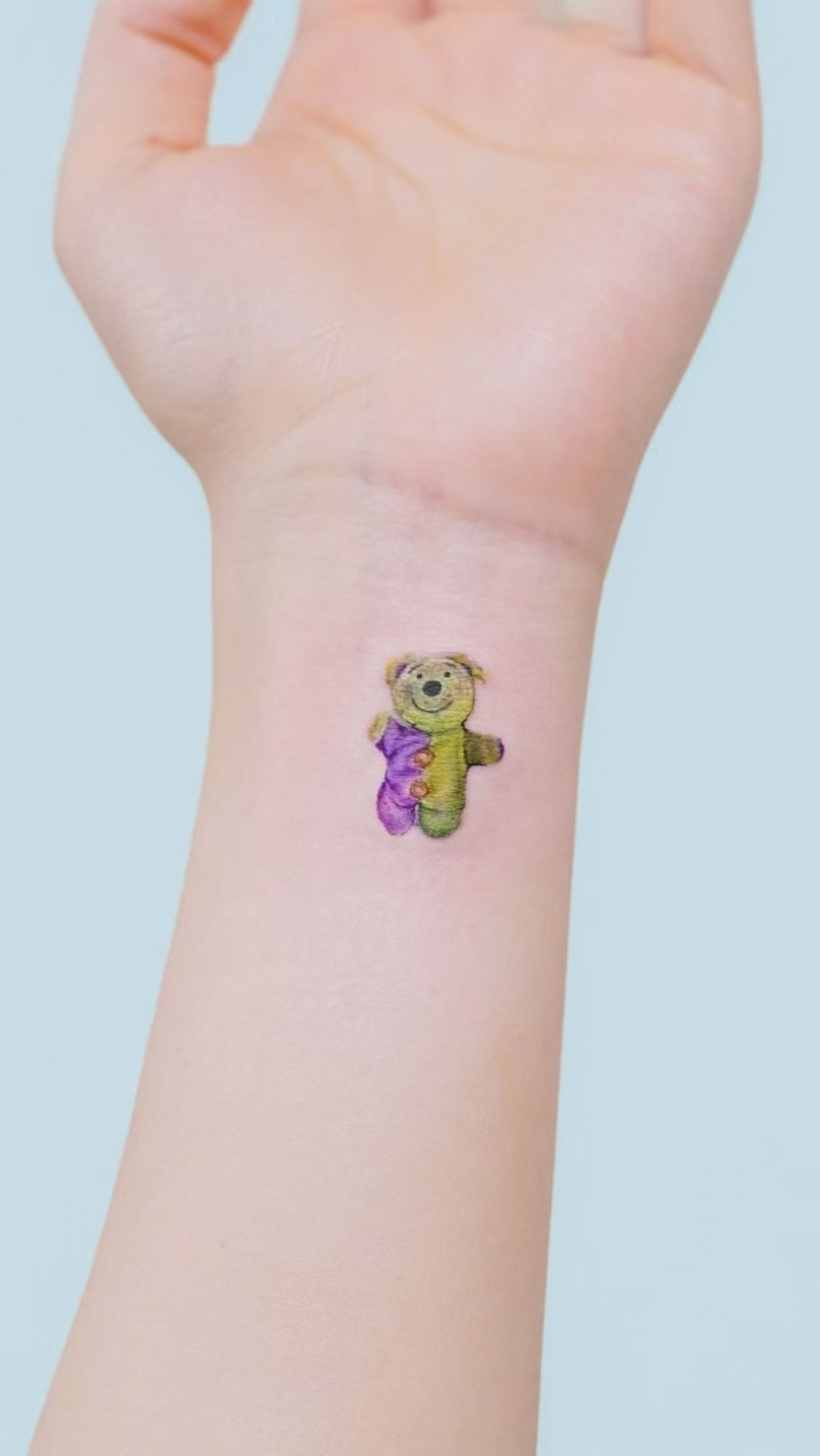 Tiny colourful bear tattoo near the wrist